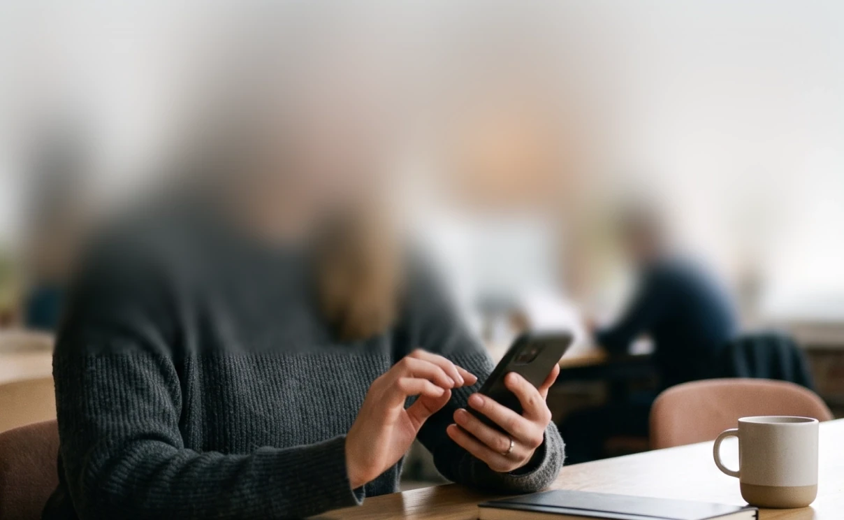 Someone messaging a business from their phone at a cafe table.
